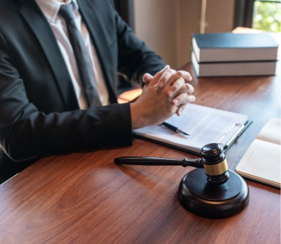 Lawyer at Work A lawyer with hands clasped at a desk with legal documents.